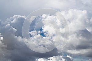 A small piece of blue sky shines through the clouds. Gray white clouds