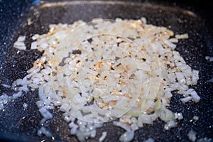 Small pieces of onion frying on a frying pan