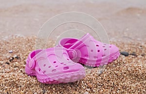 Small pink baby shoes on the sea beach