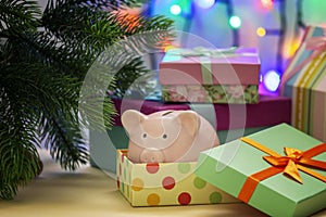 A small pink piggy bank in a festive box. Symbol of the New Year under the Christmas tree.