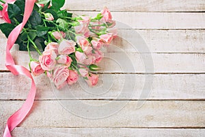 Small pink rose bouquet with ribbon on white wooden table