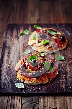 Small pizzas with mozzarella, salami and dried tomatoes