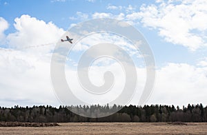 Small plane flies over field and forest
