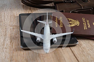 Small plane model, Thai passport, Leather bag, Tablet on wooden board background