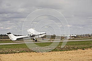 Small plane stands on the runway against the background of the forest