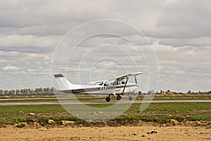 Small plane stands on the runway against the background of the forest