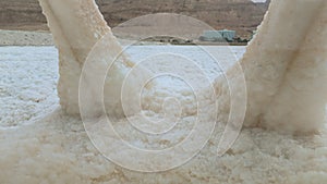 Small plastic chair completely covered with crystalline salt on shore of dead sea, only two legs visible, closeup detail, tourist