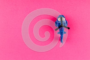 Small plastic helicopter with copy space on pink background