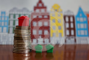 Small plastic house model on top of stacked coins
