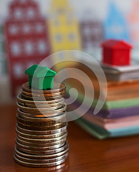 Small plastic house model on top of stacked coins