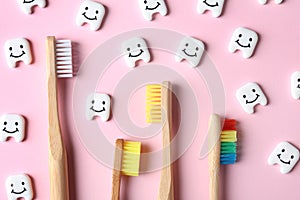 Small plastic teeth with happy faces and wooden brushes on color background