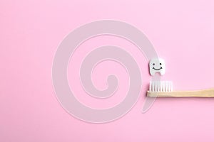 Small plastic tooth, wooden brush and space for text on color background