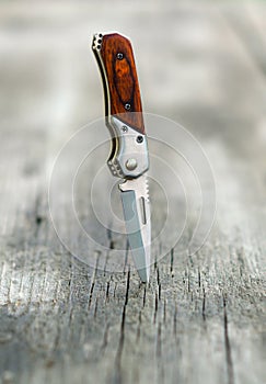 Small pocket knife stabbed into wooden table