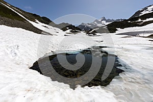 Small pond surrounded by snow in the Susten pass located in Switzerland in winter during daylight