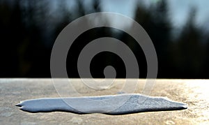 A small pool of spilled water on a metal surface. you can see the surface tension of the water rounding the edges into a small hil