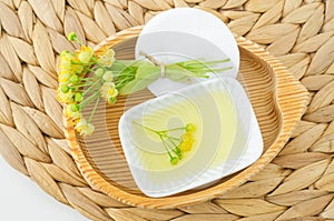 Small porcelain bowl with homemade linden (tilia, basswood, lime tree) face toner with linden flowers and cotton pad.