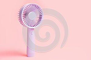 Small portable fan on pink background close-up, front view.
