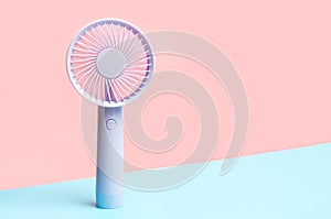Small portable mini fans on blue and pink background close-up.