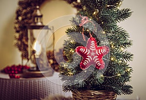 Small portable tabletop decorated Christmas tree on table  party lights illuminated  red felt fabric ornament.