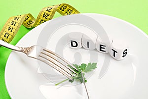 Small portion of food on big plate close-up. Small green parsley leaf on white plate with fork and knife and text diet on the