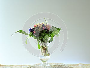 Small posy of spring flowers in a glass vase on a windowsill.