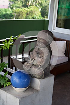 Small praying buddha statue in front of garden patio