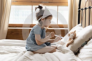 Small preschool kid girl making prick injection to fluffy toy.