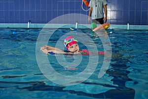 Small preschooler child learns to swim with board in pool. Swimming lesson