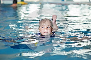 Small preschooler kid learns to swim with board in pool. Swimming lesson. Active kid plays in water