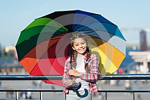 Small pretty girl standing with colorful umbrella. Girl on bridge. Hiding from sun with umbrella. Bright shades of girl