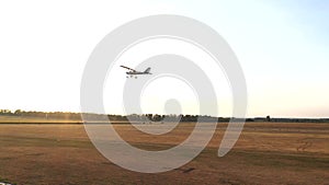 Small private airplane flying over airfield with sun flares at background. Lightweight plane is climbing. Single engine