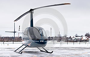 Small private blue helicopter on snowy heliport.