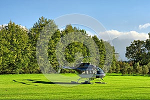 Small private helicopter on grass against mountain