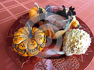Small pumpkins and gourds of various colors, displayed on platters from various angles and depth
