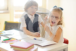 Small pupils, boy and girl, sitting at his desk.