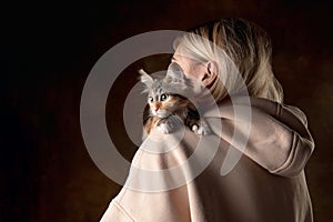 A small purebred kitten sitting on the shoulder of a young woman isolated on colored background. Flyer for ad, design.