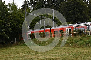 Small railway platform for passengers in local train station with red electric train