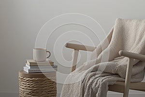 a small reading nook with a beige blanket draped over a chair and a ceramic mug of hot tea