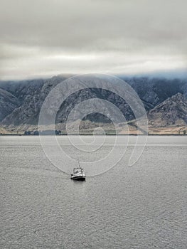 A small recreational boat on a fishing trip on a lake on the South Island of New Zealand on a cloudy morning