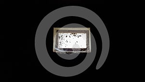 A small rectangular dirty and dusty web window in a large basement. White light penetrates the dark basement