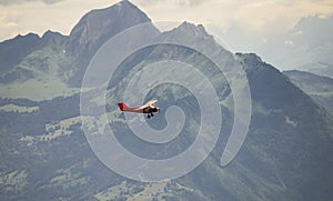 A small red airplane flying over the Alps