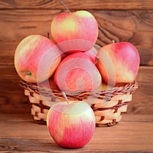 Small red apples on a wooden table and in a basket. Brown wooden background. Apples photo. Healthy natural dessert