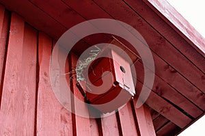 Small red bird house with nest on top