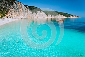 Small red boat on clear blue sea water near to amazing beach on mediterranean island. Summer beach vacation relaxation concept