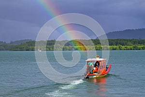 Small red boat on the river with rainbow