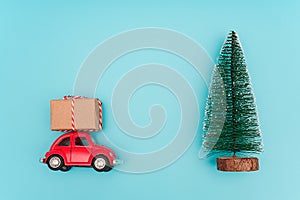 Small red car carries gift box. Concept delivery of gifts or purchases. Minimal style Top view Creative flat lay Template for