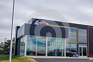 A small red car is seen on the roof of a building with large windows.