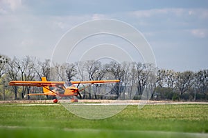 Small red charter airplane waiting on a green field to take off photo