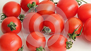 Small red Cheri tomatoes with green tails lie scattered on a white background