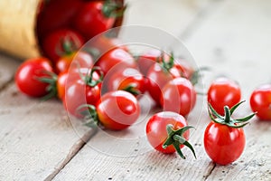 Small red cherry tomatoes spill out of a wicker basket